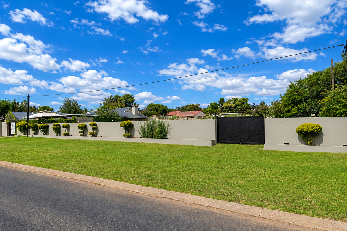 Street view of the restaurant property featuring a well-maintained perimeter wall, gated entrance, and manicured lawn area.