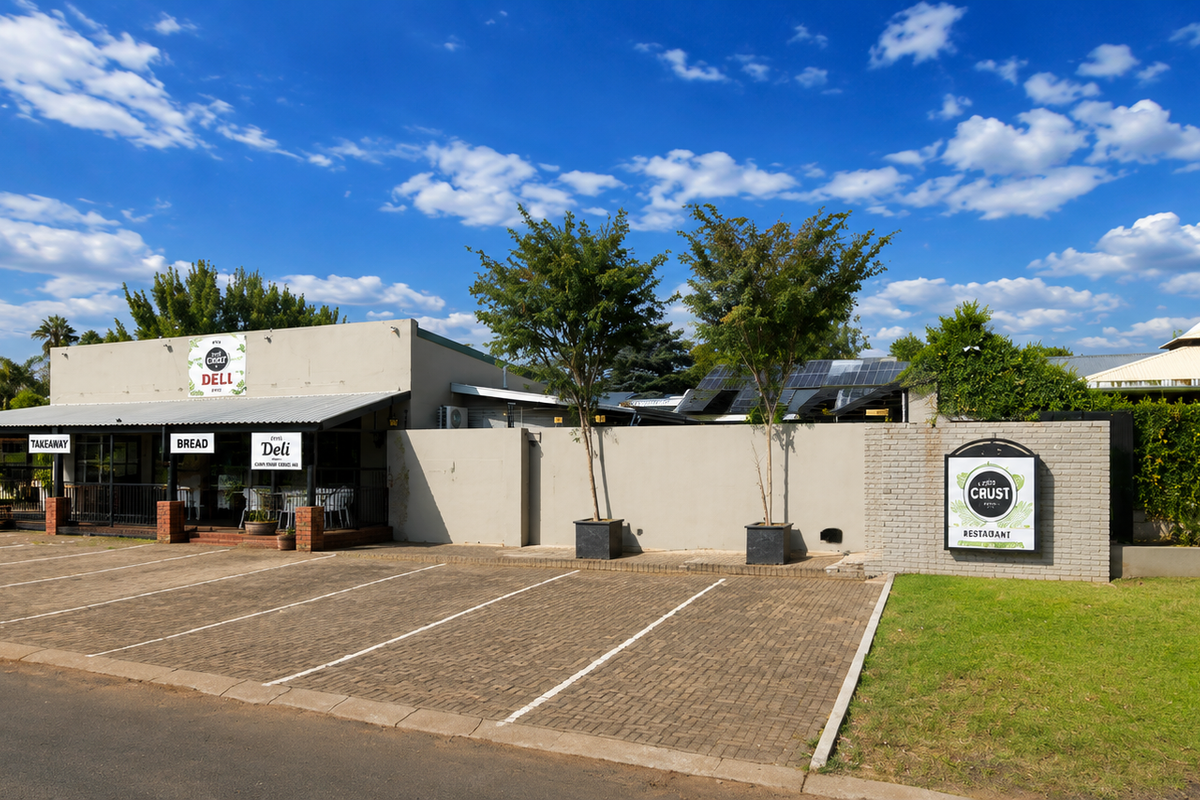 Front exterior view of the restaurant property featuring a paved parking area, covered patio entrance, and well-maintained boundary walls.