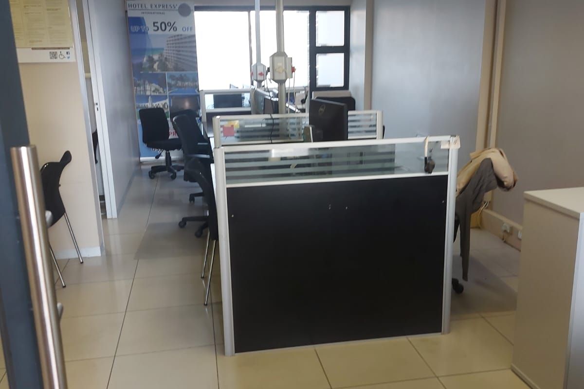 A functional office space featuring tiled flooring, a suspended ceiling, and built-in partition cubicles, providing a practical layout for a professional work environment.