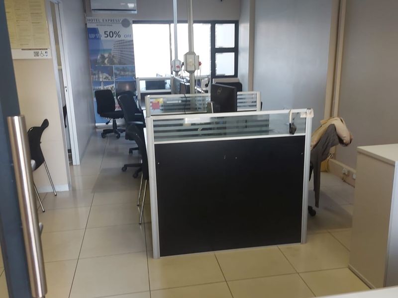 A functional office space featuring tiled flooring, a suspended ceiling, and built-in partition cubicles, providing a practical layout for a professional work environment.