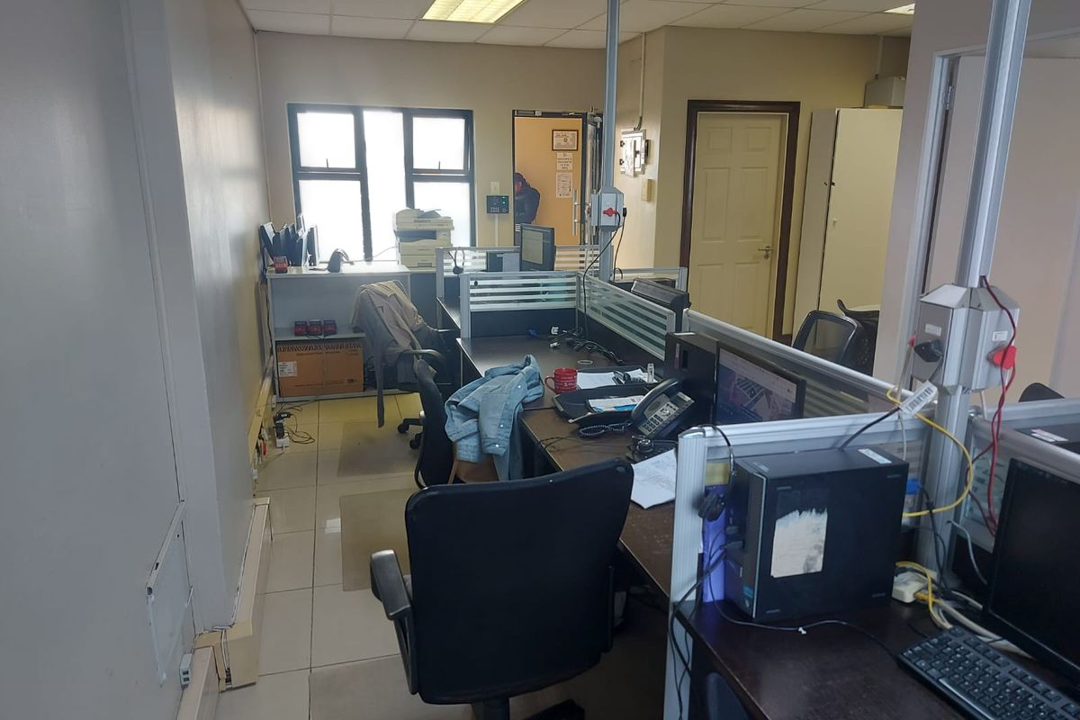 A functional office space featuring tiled flooring, suspended ceiling, and integrated workstation partitioning, suitable for a professional work environment.
