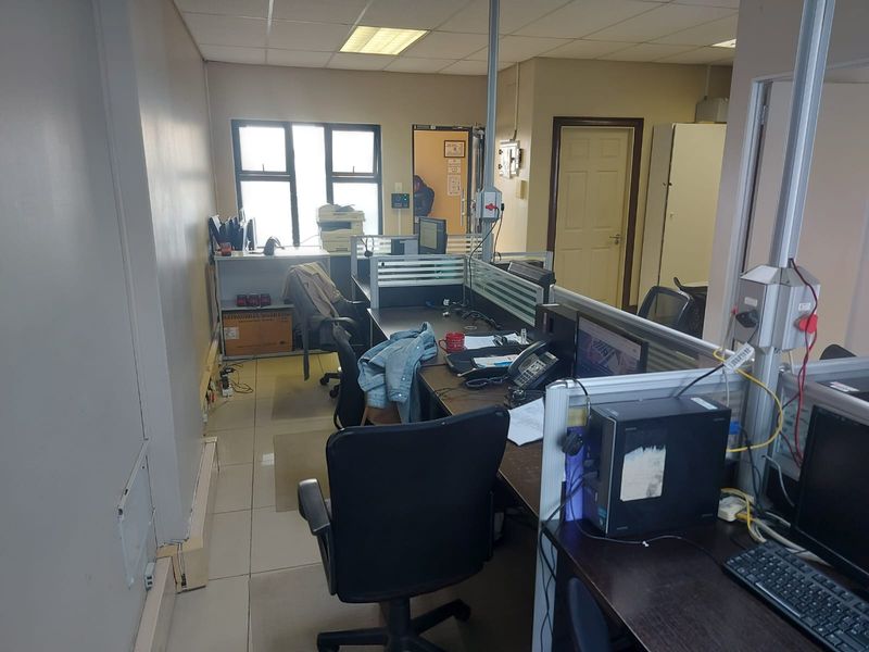 A functional office space featuring tiled flooring, suspended ceiling, and integrated workstation partitioning, suitable for a professional work environment.