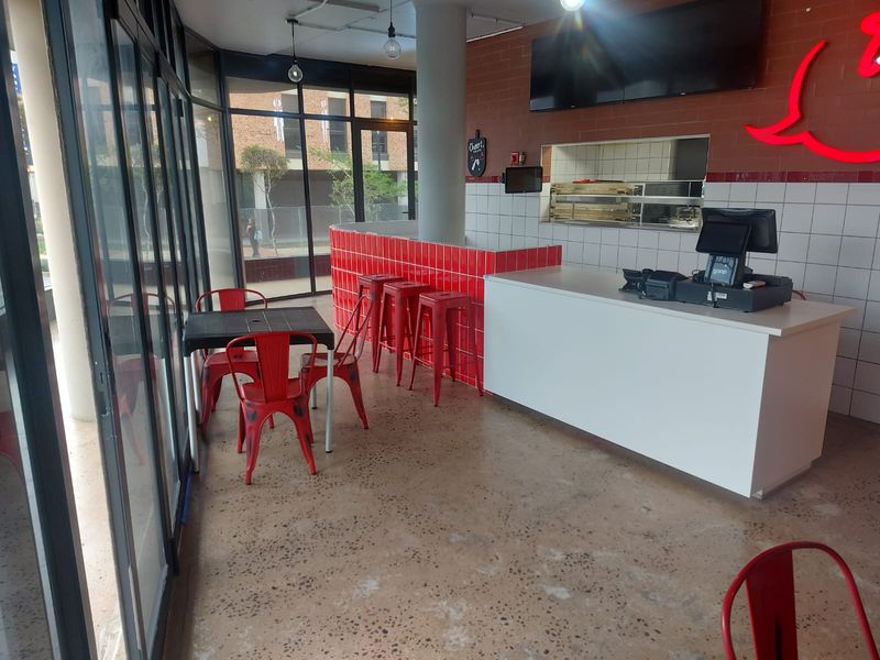 A retail space featuring polished concrete floors, a tiled service counter, and large glass windows providing ample natural light and street visibility.