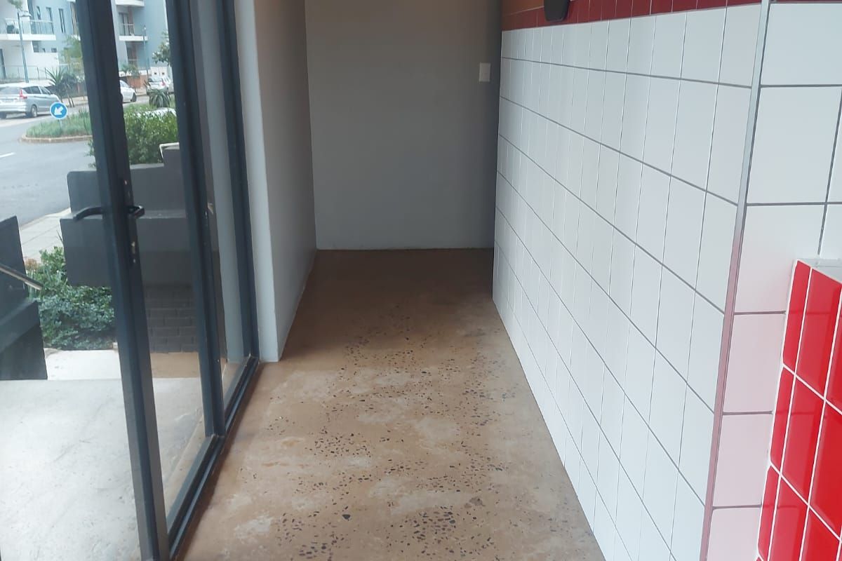 An entry area featuring polished concrete floors, tiled wall accents, and exposed industrial ducting, providing a clean, modern retail space.
