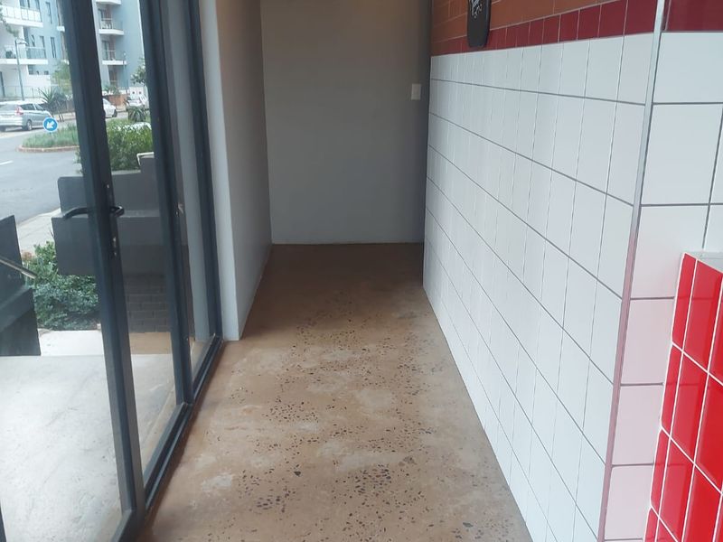 An entry area featuring polished concrete floors, tiled wall accents, and exposed industrial ducting, providing a clean, modern retail space.