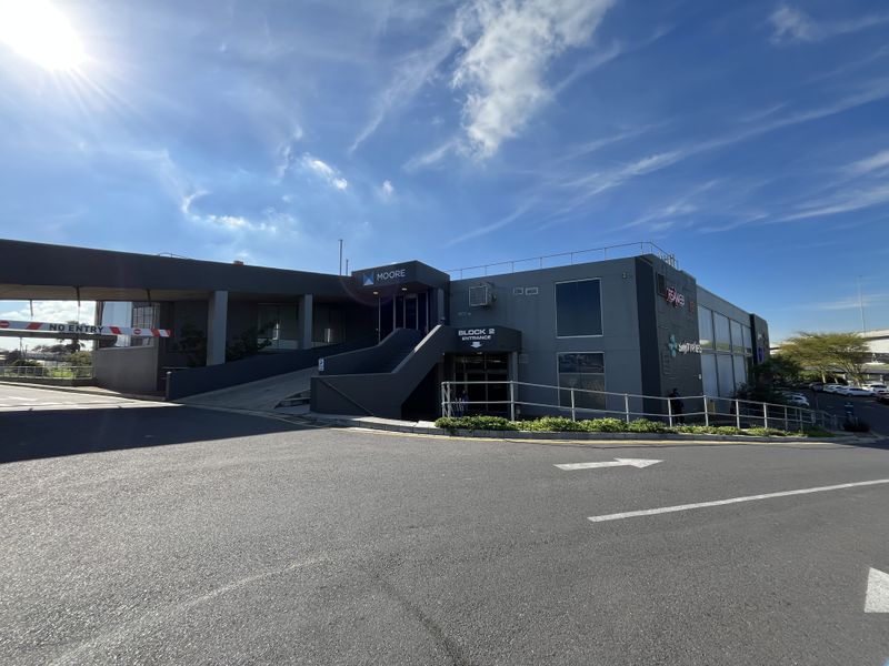 Exterior view of the office building entrance, featuring a concrete ramp, metal railings, and clear signage for Block 2.