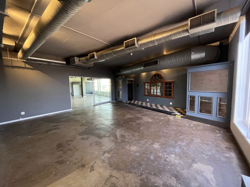 Spacious open-plan office area featuring industrial exposed ductwork, polished concrete floors, and unique built-in cabinetry with a checkered tile accent.