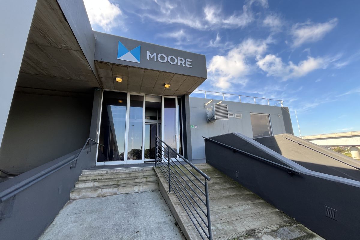 Front entrance of the office building featuring concrete stairs, metal handrails, and prominent signage.