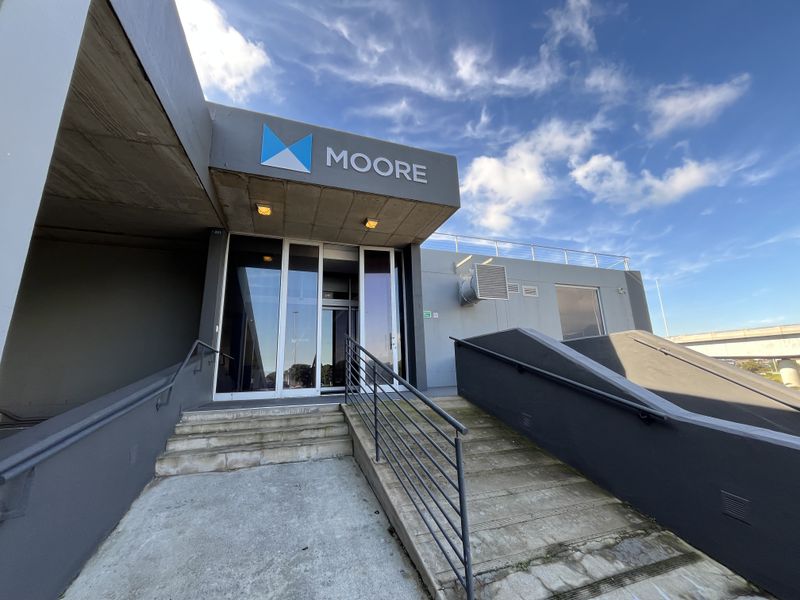 Front entrance of the office building featuring concrete stairs, metal handrails, and prominent signage.