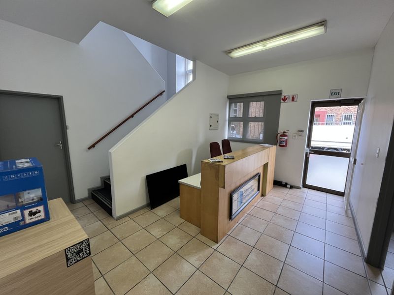 Industrial entry area featuring a built-in reception desk, tiled flooring, and a staircase leading to the upper level.