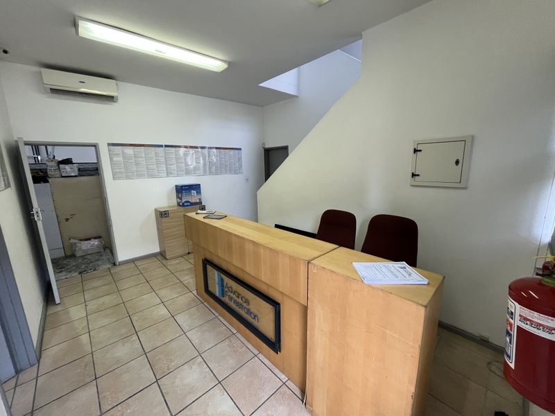Functional industrial reception area featuring ceramic tiled flooring, a built-in reception desk, and split-system air conditioning.