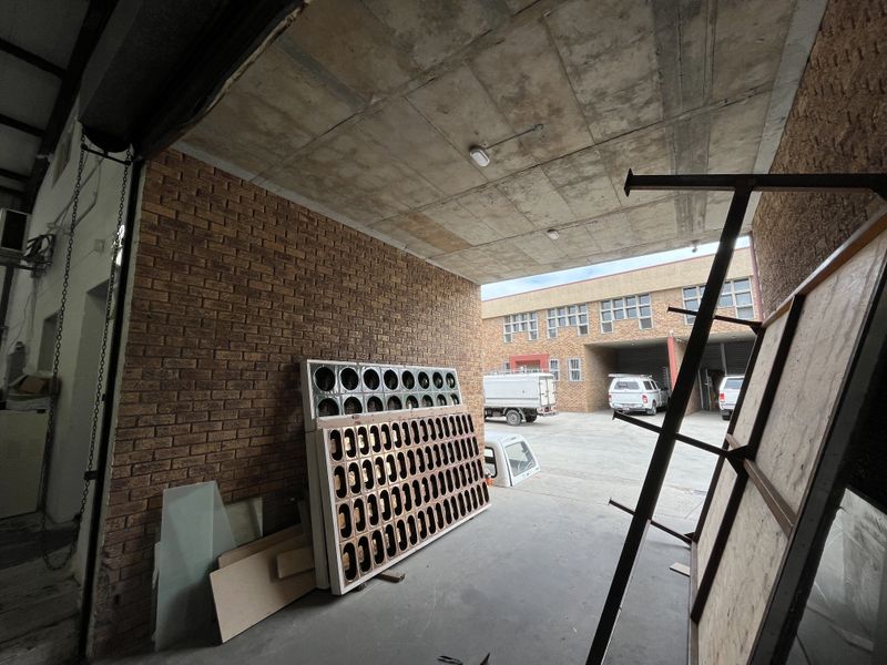 Spacious industrial garage area featuring exposed concrete ceilings, face brick walls, and durable concrete flooring, suitable for storage or workshop use.