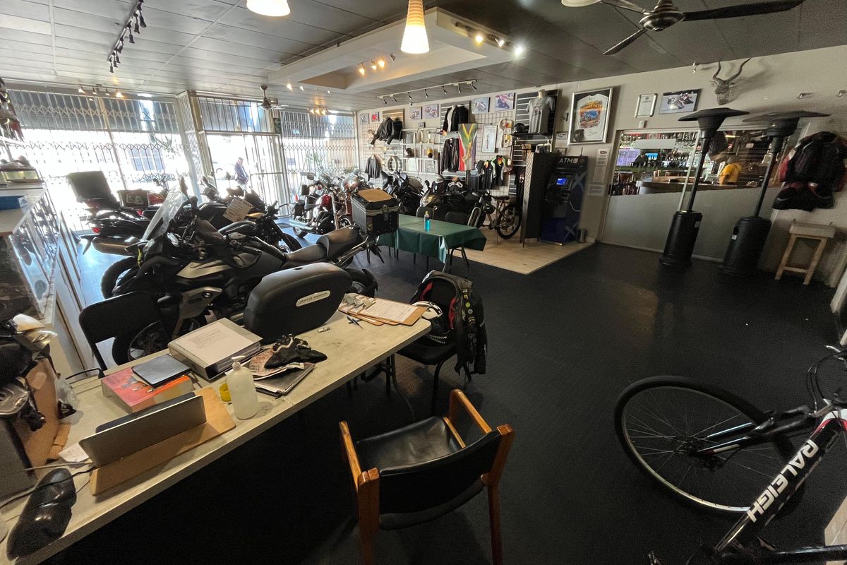 Open-plan commercial showroom space featuring track lighting, recessed ceiling lights, and secure street-facing access, currently utilized for motorcycle display and retail operations.