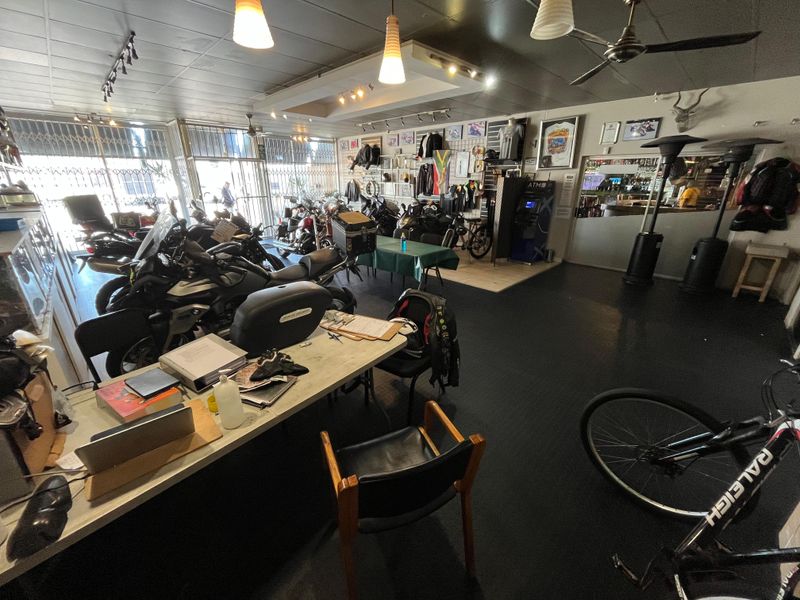 Open-plan commercial showroom space featuring track lighting, recessed ceiling lights, and secure street-facing access, currently utilized for motorcycle display and retail operations.