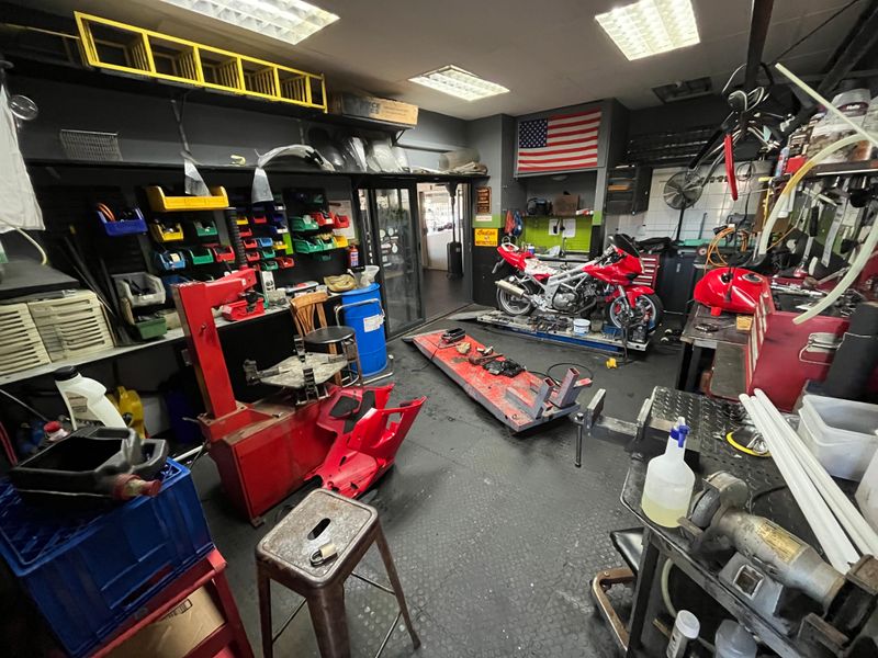 A functional workshop or garage space featuring durable rubber flooring, built-in storage shelving, and integrated lighting, suitable for automotive maintenance and repair activities.
