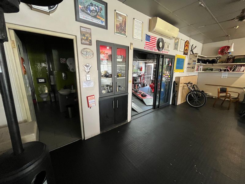 Utility space featuring rubber flooring, a built-in display cabinet, split-system air conditioning, and direct access to an adjacent restroom and workshop area.