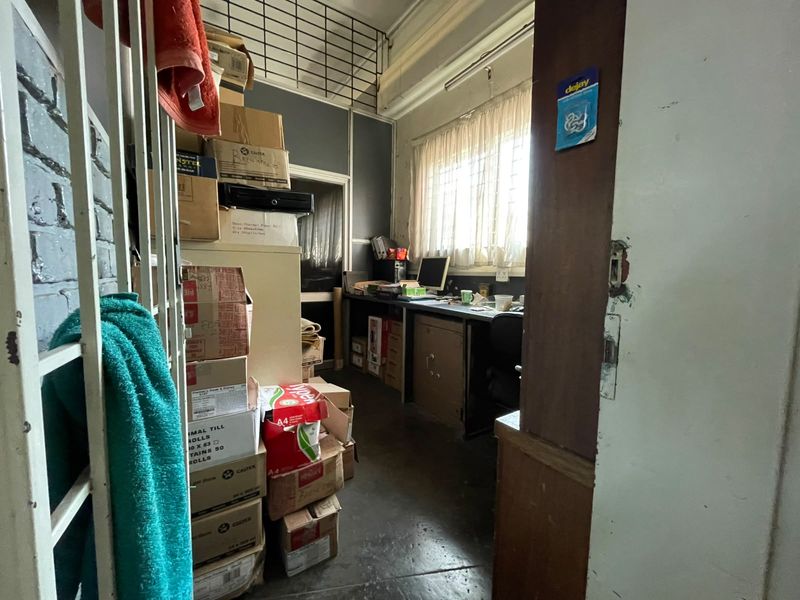 A functional office space featuring a built-in desk, security bars on the window, and direct access, currently utilized for storage.
