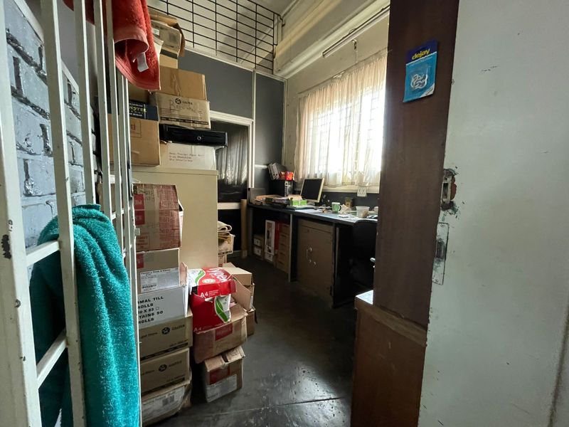 A functional office space featuring a built-in desk, window security bars, and a security gate, currently used for storage.