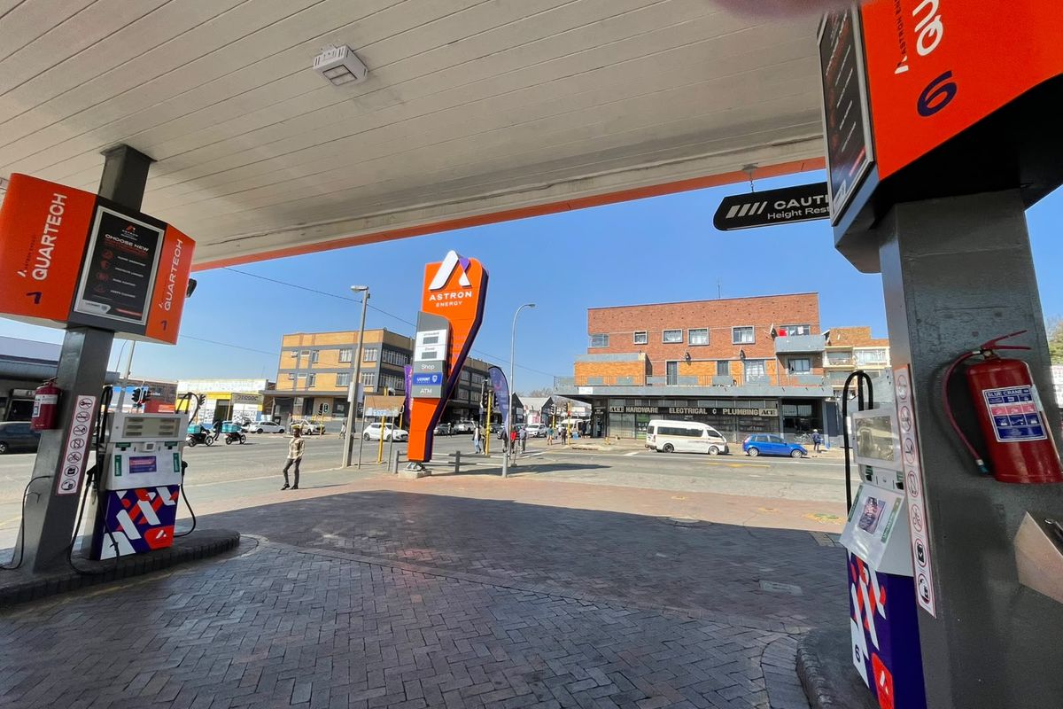 A view of a commercial fuel station forecourt featuring multiple fuel pumps, a protective overhead canopy, and paved ground surface.