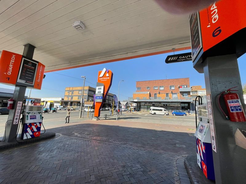 A view of a commercial fuel station forecourt featuring multiple fuel pumps, a protective overhead canopy, and paved ground surface.