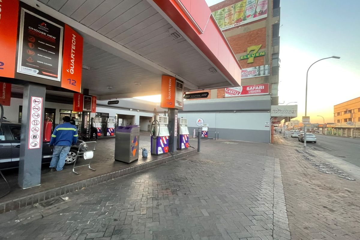 A functional petrol station forecourt featuring multiple fuel pumps, a protective canopy, and paved surfacing, situated along a busy street.