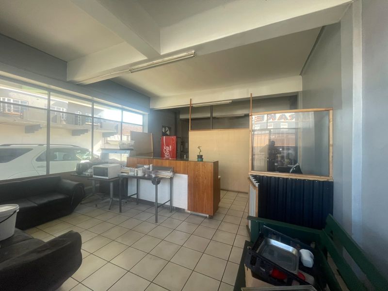 Open-plan retail space featuring large display windows, tiled flooring, and a built-in service counter, suitable for various commercial business applications.