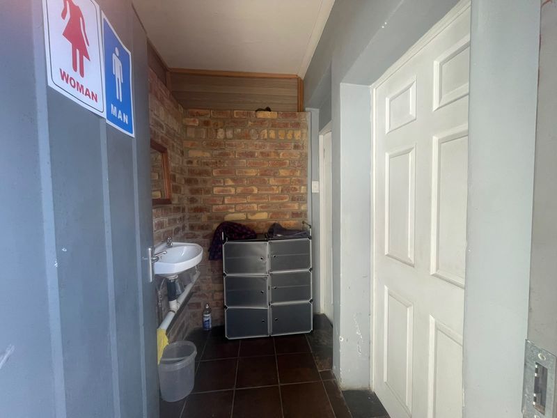 A functional restroom area featuring exposed brickwork, a wall-mounted basin, and tiled flooring, providing basic utility for a retail environment.