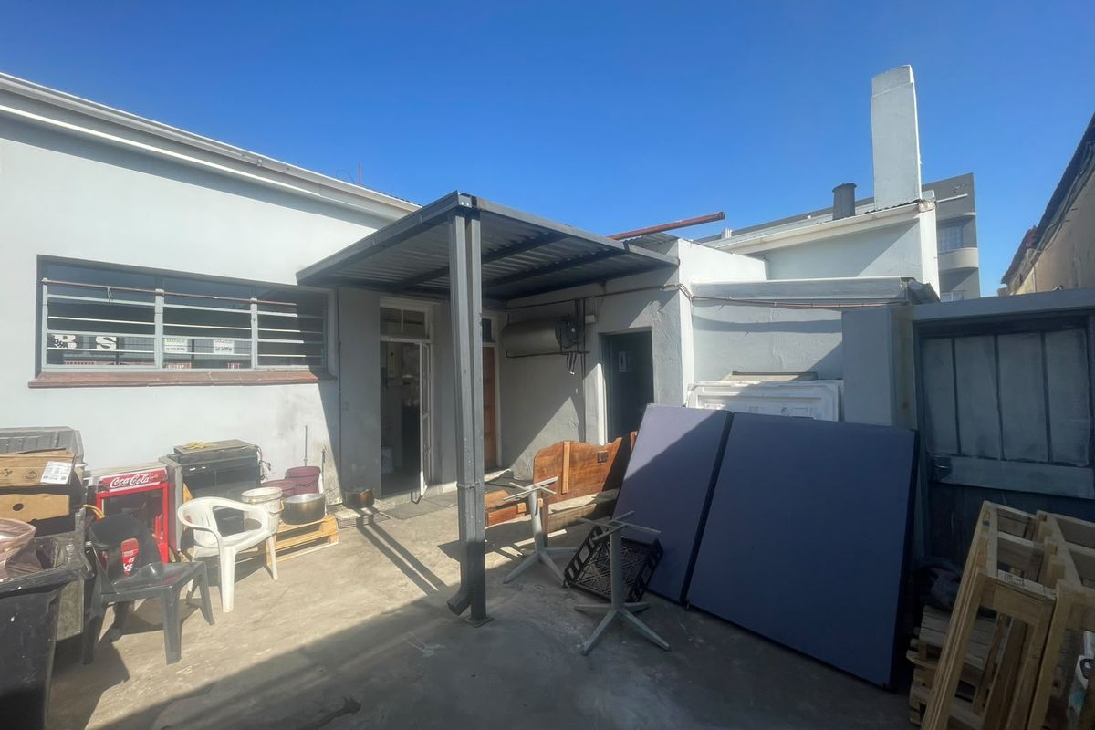 Rear exterior area featuring a metal patio cover, concrete flooring, and access to the main building structure.