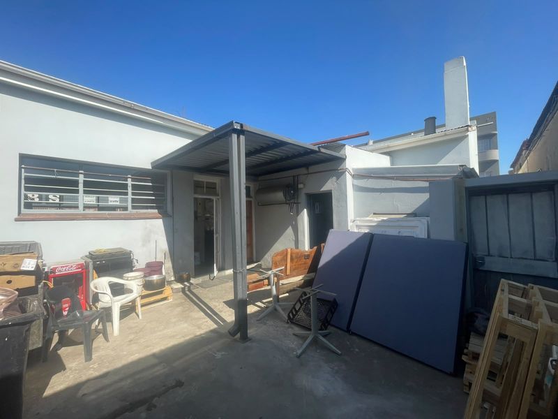 Rear exterior area featuring a metal patio cover, concrete flooring, and access to the main building structure.