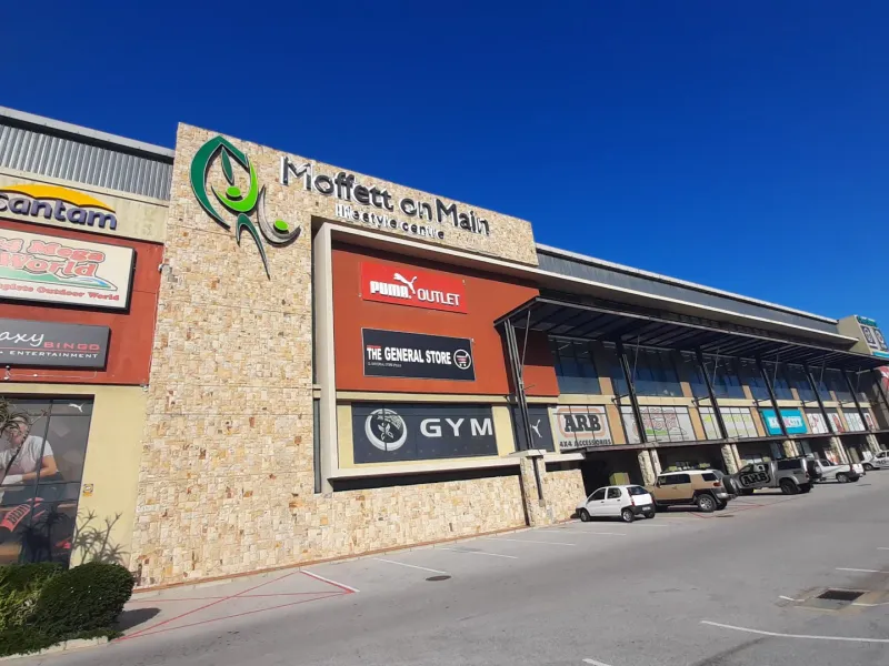 Front elevation of the Moffett on Main lifestyle centre, featuring stone cladding, prominent commercial signage, and an extensive paved parking area.