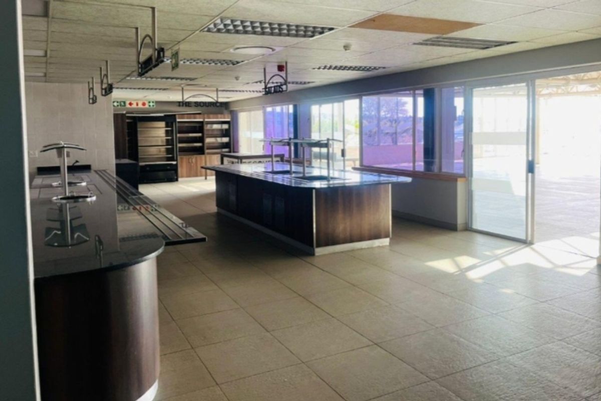 Spacious commercial kitchen area featuring built-in serving counters, tiled flooring, and large sliding glass doors providing ample natural light.
