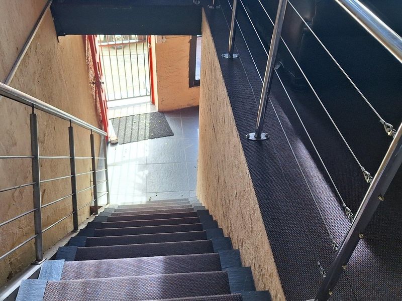 A staircase featuring a stainless steel balustrade and carpeted steps, leading down to a secure entrance area.