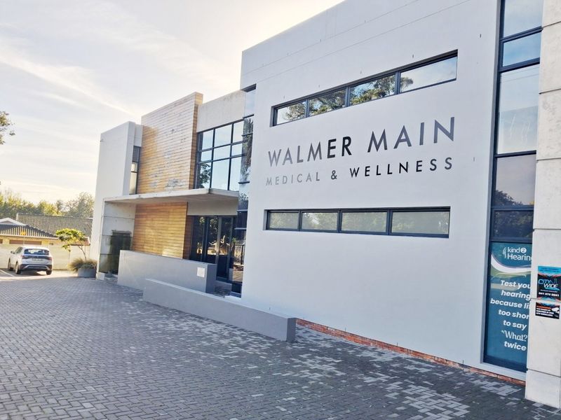 Modern commercial medical and wellness facility exterior featuring clean white render, timber accents, and paved driveway access.
