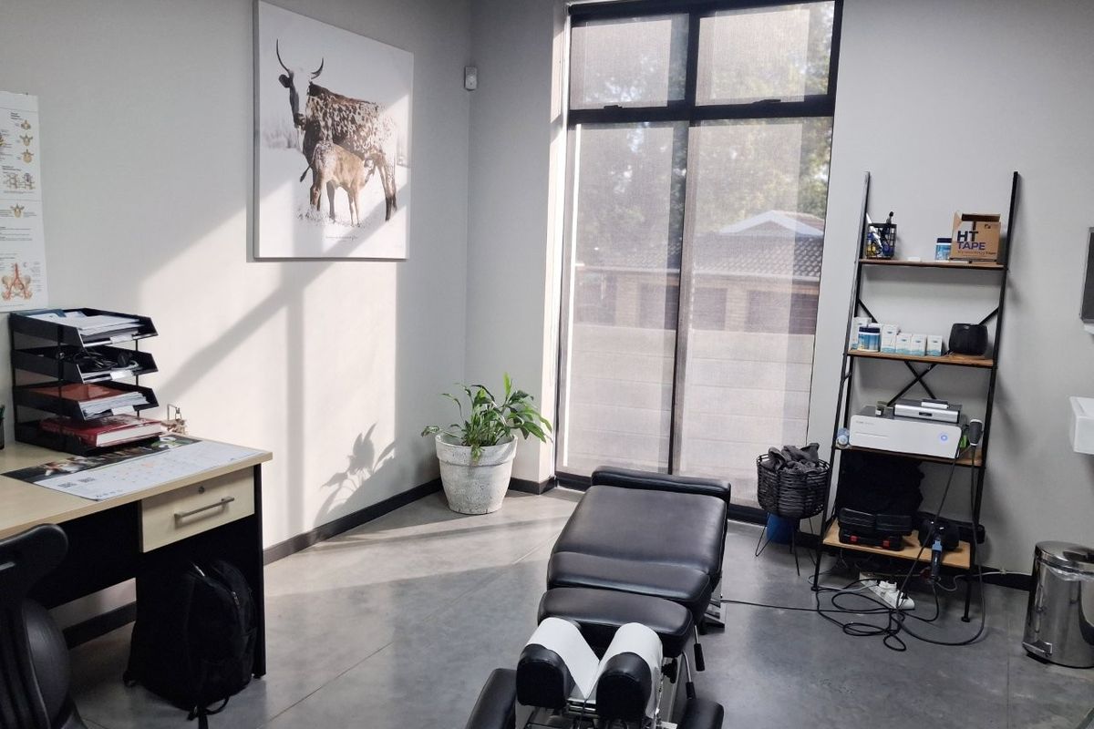 A professional commercial office or treatment room featuring polished concrete floors, neutral walls, and a large window providing natural light.