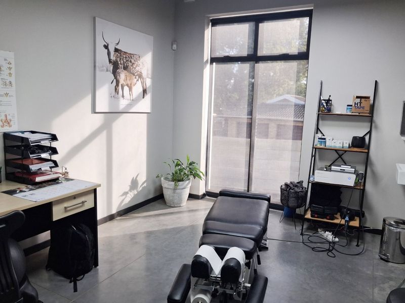 A professional commercial office or treatment room featuring polished concrete floors, neutral walls, and a large window providing natural light.