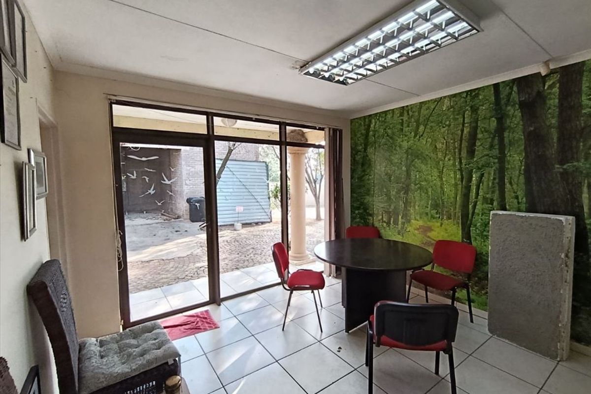 A functional living area featuring tiled flooring, a large sliding glass door providing outdoor access, and a central fluorescent light fixture.