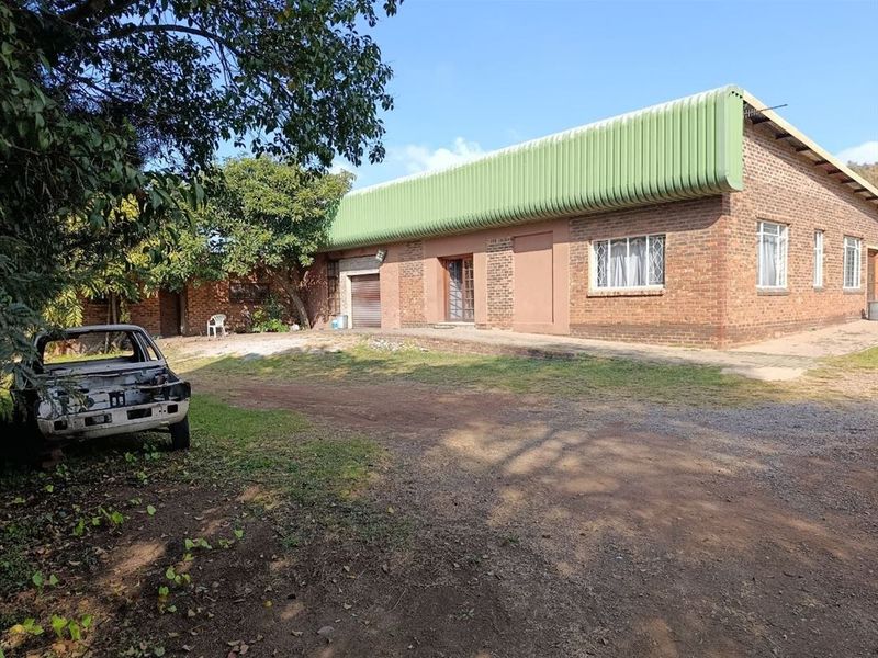 Front exterior view of an industrial brick building featuring a corrugated metal roof, roller shutter door, and security-fitted windows.