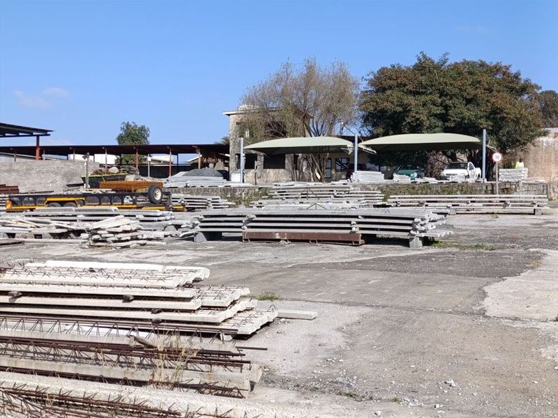 Industrial yard area featuring concrete paving, shade cloth structures, and perimeter walling, suitable for storage or operational use.
