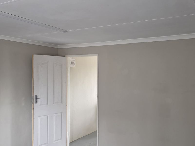 A clean, neutral-toned office space featuring a coved ceiling, fluorescent lighting, and a white panelled door leading to an adjacent area.