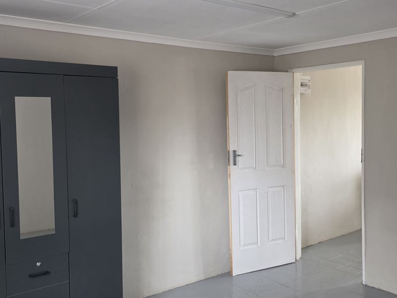 A functional office space featuring neutral wall finishes, tiled flooring, and a standard interior door leading to an adjacent area.