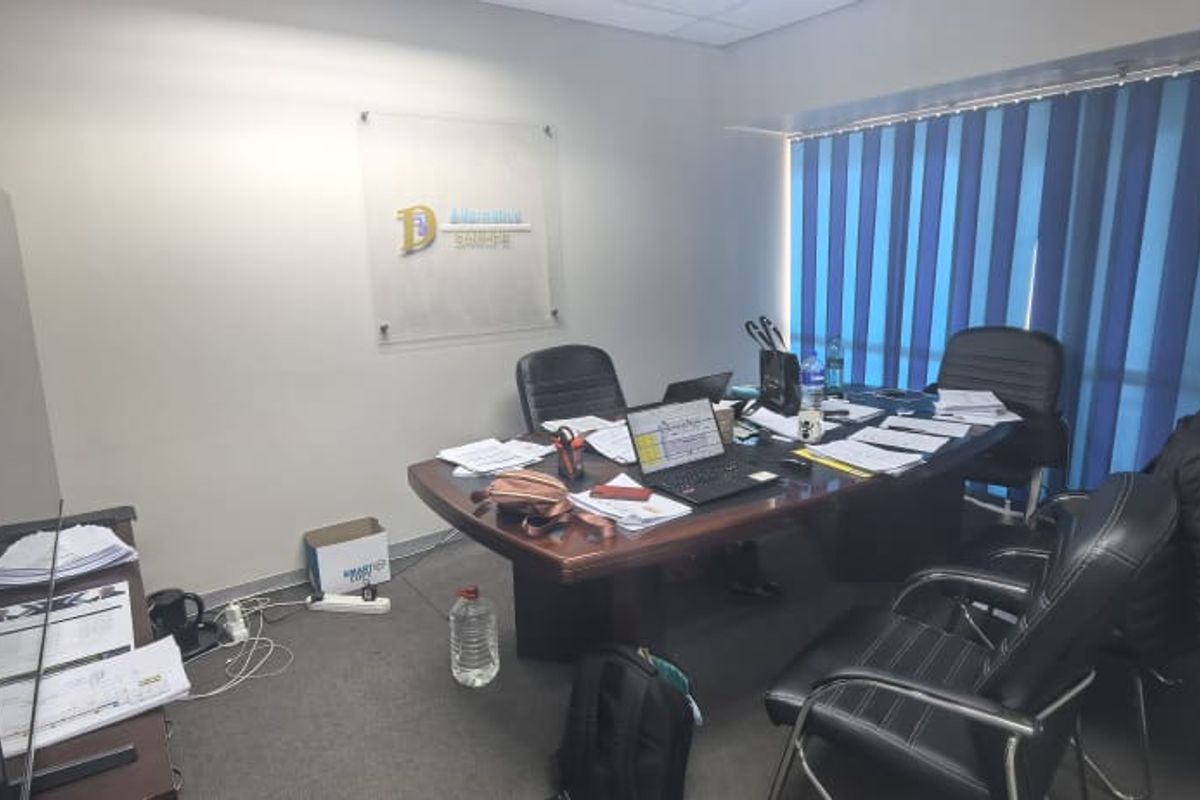 A functional office space featuring carpeted flooring, a suspended ceiling, and vertical window blinds, suitable for professional use.