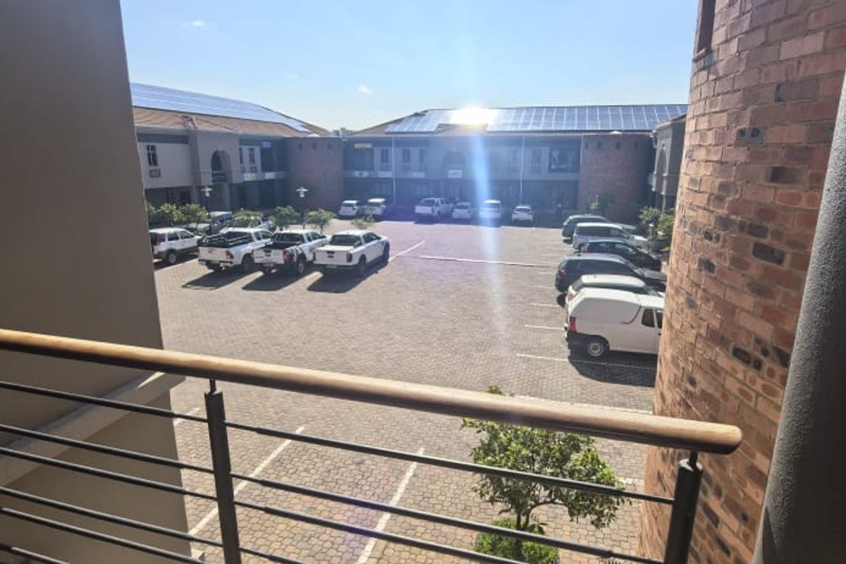 View of the office complex parking area from an elevated balcony, featuring brick architecture and solar panel installations.