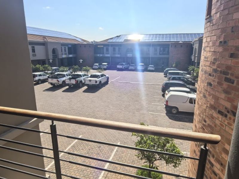 View of the office complex parking area from an elevated balcony, featuring brick architecture and solar panel installations.