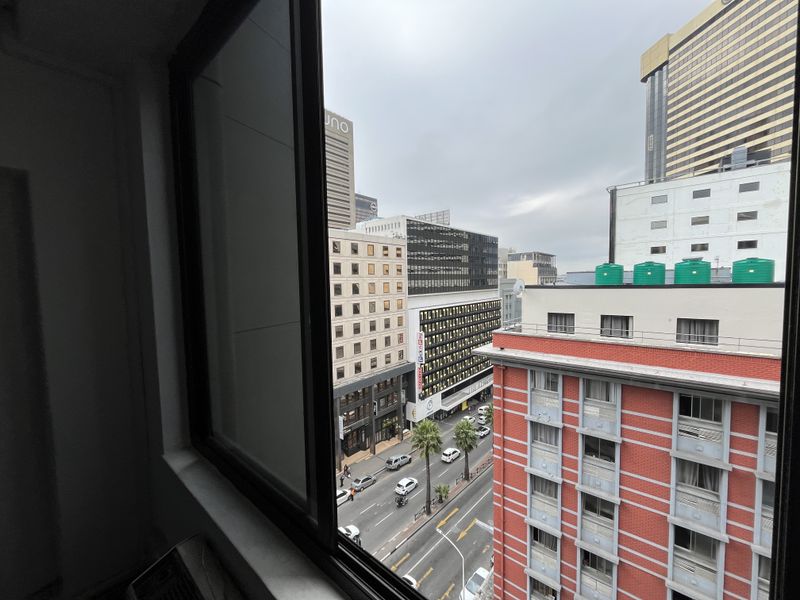 An elevated urban view looking out from an office window over the surrounding city street and neighboring commercial buildings.
