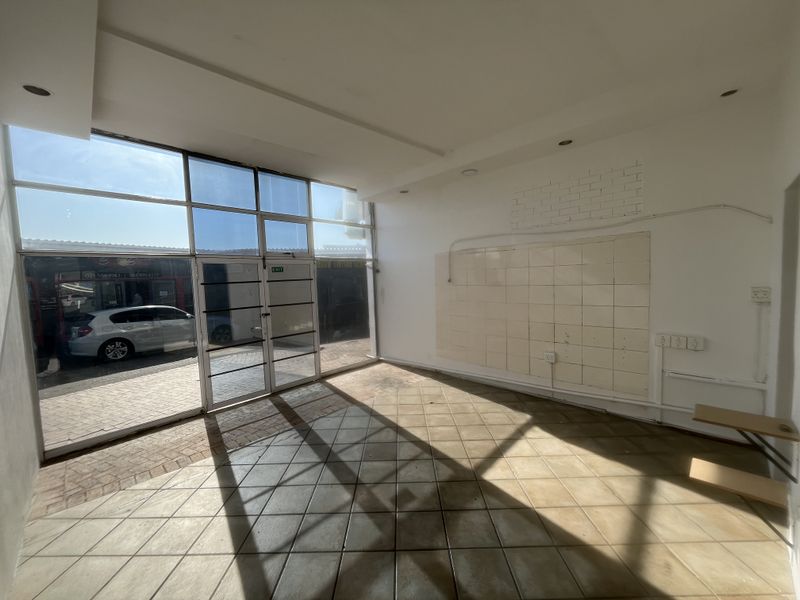 Empty commercial storefront space featuring large glass windows, tiled flooring, and recessed lighting, suitable for a retail or office setup.