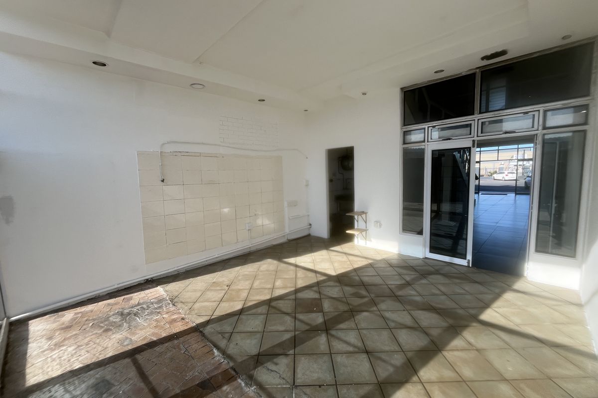 An empty commercial entry space featuring tiled flooring, recessed lighting, and a glass storefront entrance, currently requiring cosmetic updates and repairs.