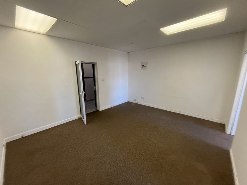 An empty office space featuring a drop ceiling with recessed lighting and brown carpet flooring, providing a blank canvas for professional use.
