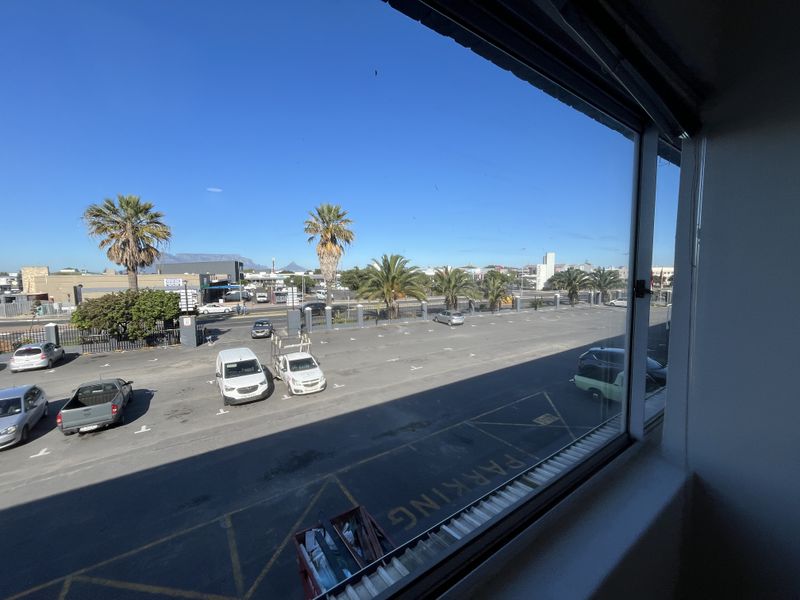 A clear view from an office window overlooking a paved parking area and surrounding neighborhood.