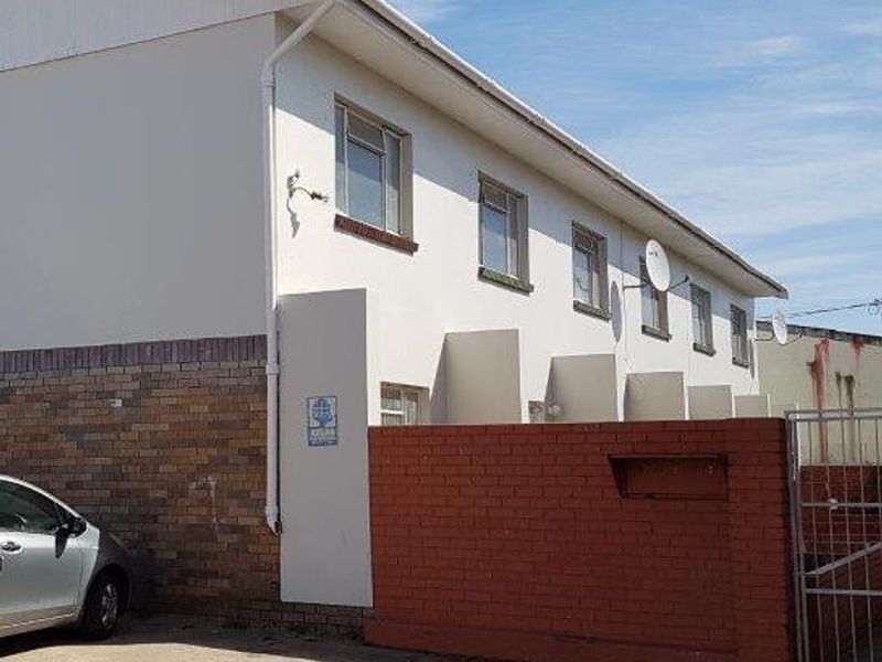 Exterior view of an apartment complex featuring a brick and painted facade with a concrete driveway and gated entrance.