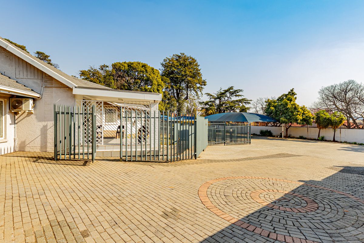Spacious paved rear exterior area featuring secure fencing, a covered patio, and an external air conditioning unit.